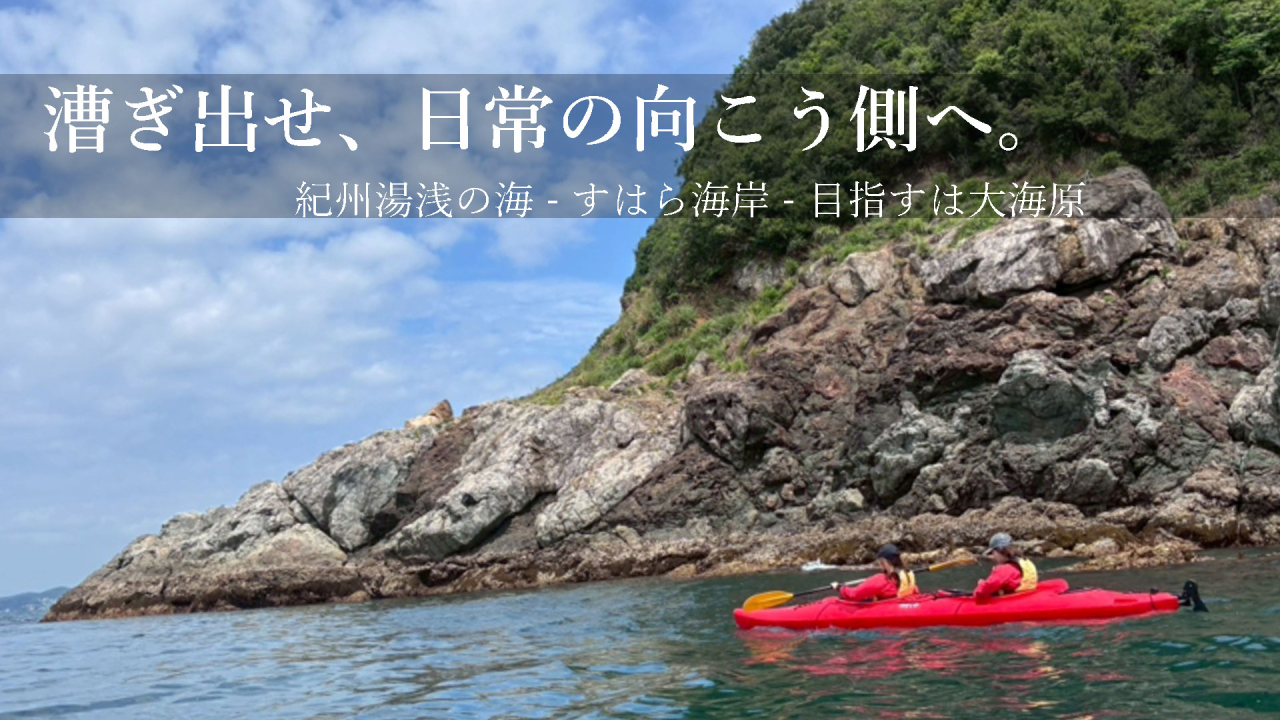 和歌山県湯浅町の広大な海をカヤックで進む冒険ツアーの様子。青い空と切り立った岩肌が美しいシーサイドビュー。